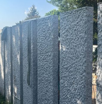 Hohe Gabionenwand mit Natursteinen als stilvoller Sichtschutz im Garten.