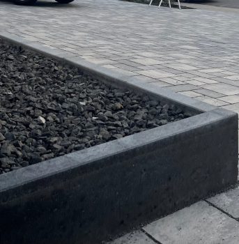 Dunkle Steinbegrenzung für Beete und Grünflächen.
